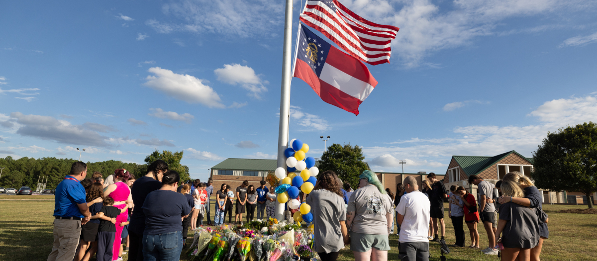 Students and community members make a prayer circle around a makeshift memorial outside of Apalachee High School on September 5, 2024 in Winder, Georgia. Two students and two teachers were shot and killed at the school on September 4, and a 14-year-old suspect, who is a student at the school, is in custody.   Jessica McGowan/Getty Images/AFP (Photo by Jessica McGowan / GETTY IMAGES NORTH AMERICA / Getty Images via AFP)