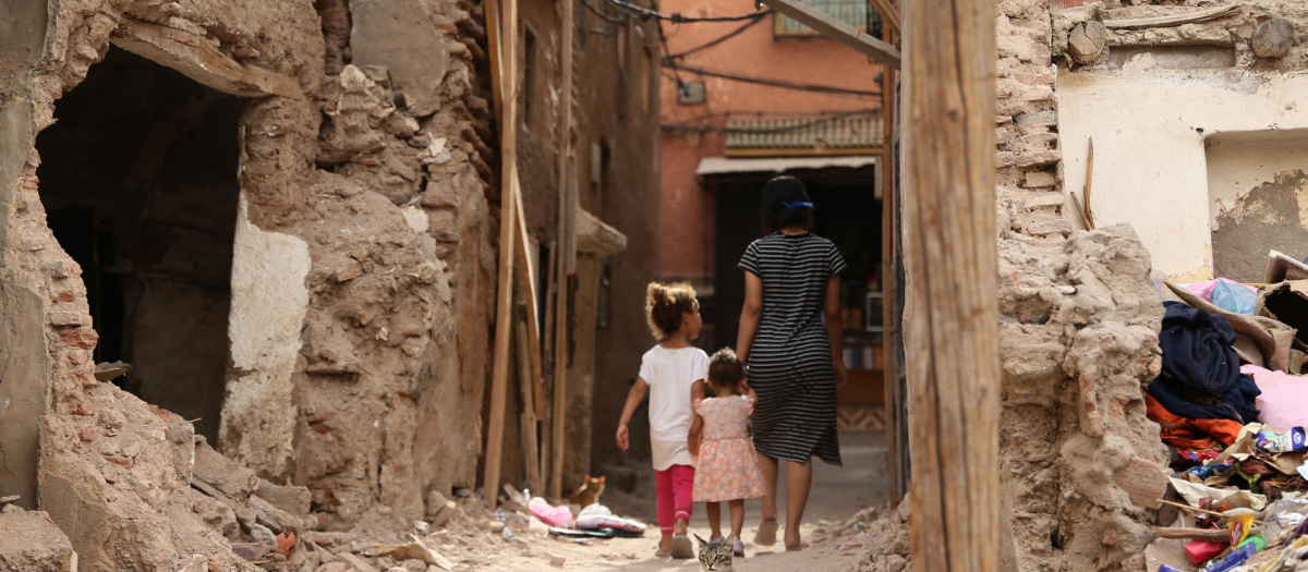 Una familia pasea entre casas destruidas por el terremoto que azotó hace un año la región de Marrakech (Marruecos)