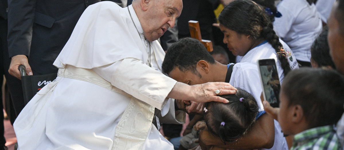 Pope Francis (L) blesses a man and his child during his visit to the Irmas Alma School for Children with Disabilities in Dili on September 10, 2024. (Photo by Tiziana FABI / AFP)