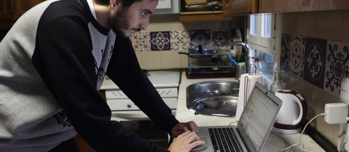 Una persona teletrabaja en la cocina de su domicilio.