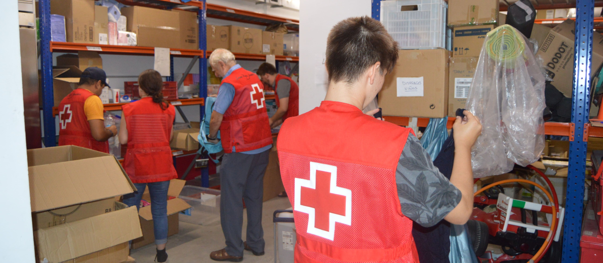 Voluntarios de Cruz Roja preparan lotes de material escolar para su reparto