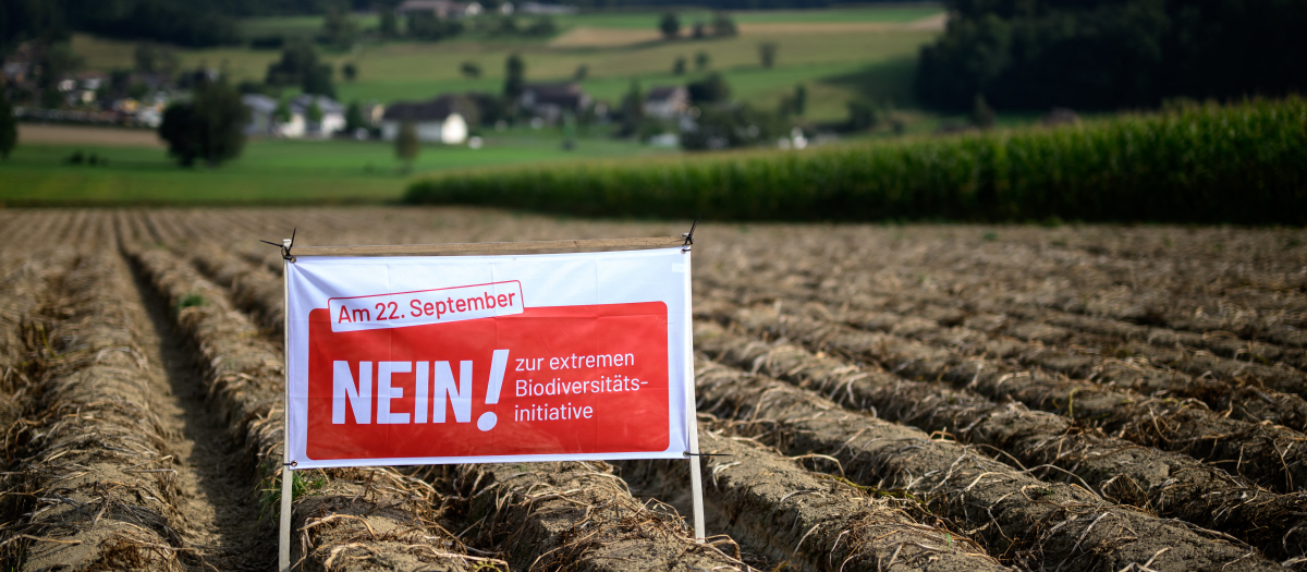 En esta fotografía, un agricultor coloca una pancarta electoral en la que se lee "¡No a las iniciativas extremas de biodiversidad!"