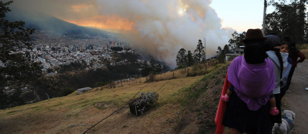 Personas observan un incendio forestal este martes, en el sector de Guápulo en Quito (Ecuador)