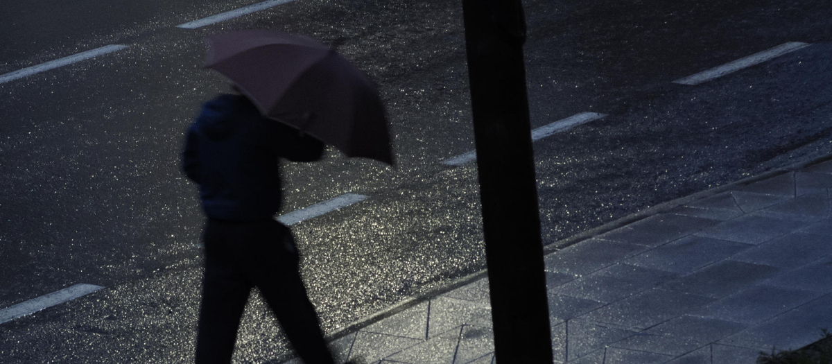 Un hombre se protege del viento y de la lluvia con un paraguas este jueves en Palas de Rei (Lugo)