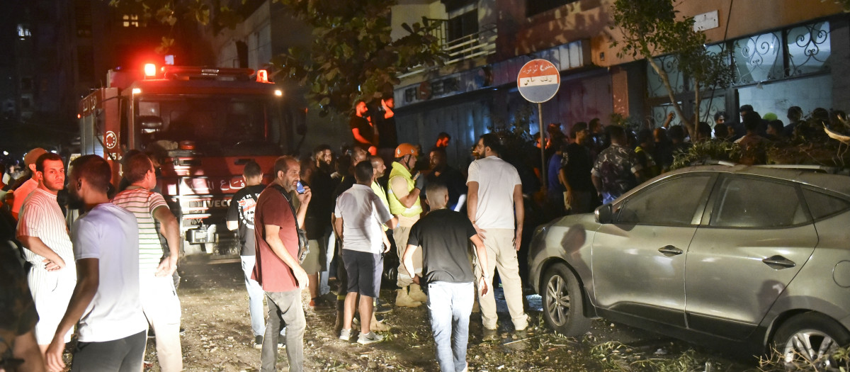 La gente se reúne en el exterior de un edificio de apartamentos que fue alcanzado por un ataque aéreo israelí en el distrito de Beirut