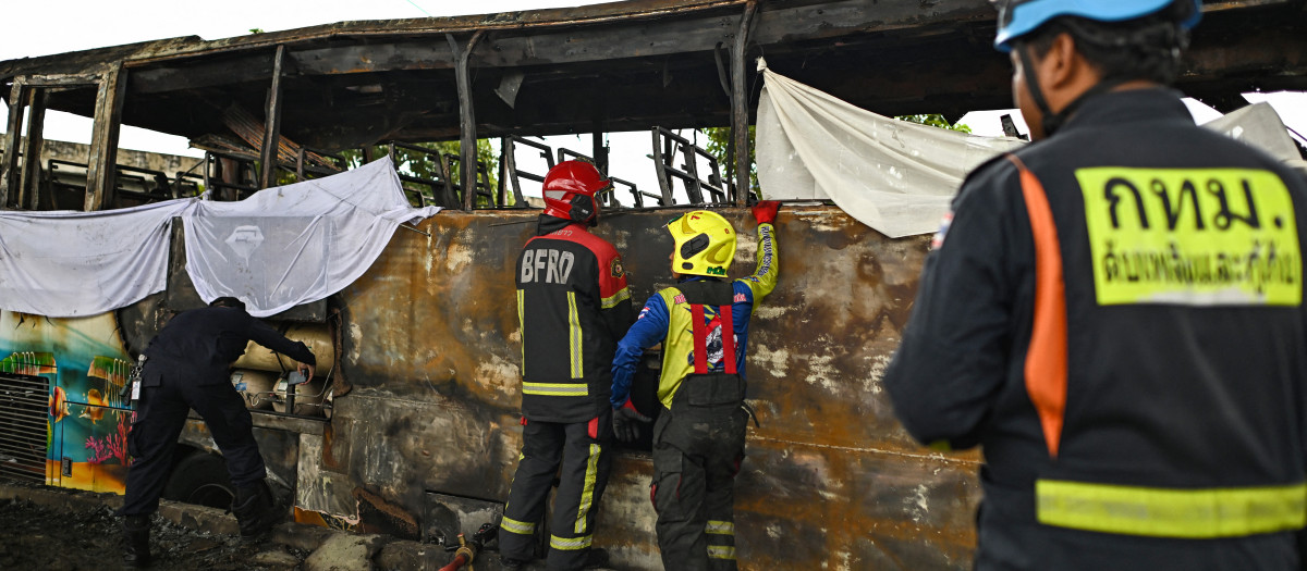 Bomberos y rescatistas inspeccionan un autobús incendiado que transportaba a estudiantes y profesores en las afueras de Bangkok, Tailandia