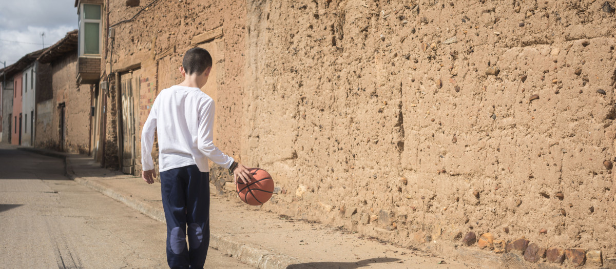 Un niño juega en una calle desierta de un pueblo