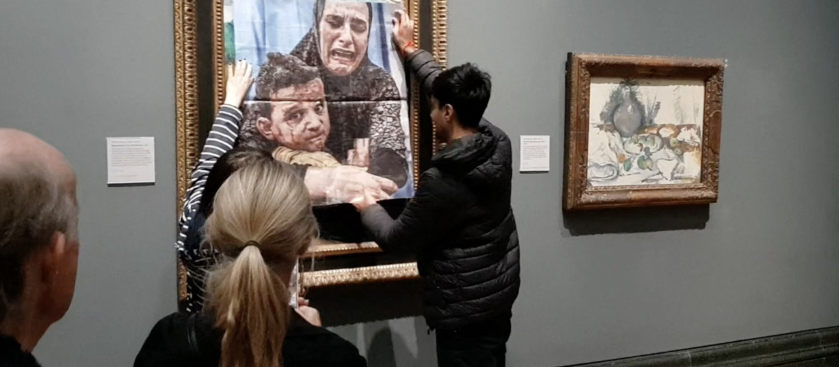 una activista pegando una foto de una madre y un niño de Gaza sobre la obra de arte de Picasso titulada "Maternidad", en la Galería Nacional en el centro de Londres