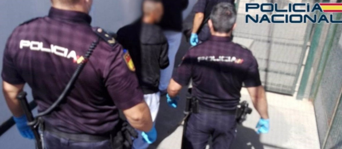 Agentes de Policía, junto al detenido tras la muerte de un hombre hallado en una patera con destino Almería junto a otros 16 inmigrantes