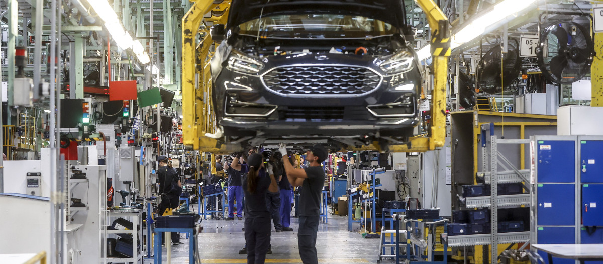 Dos trabajadores con un vehículo de la fábrica de Ford en Almussafes, Valencia, Comunidad Valenciana (España)