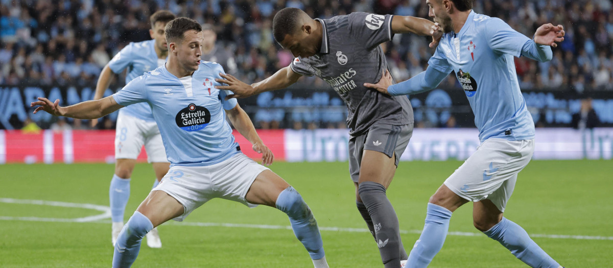 El delantero del Real Madrid Kylian Mbappé (c) juega un balón entre Óscar Mingueza (d) y Javier Manquillo, ambos del Celta, durante el partido de la décima jornada de LaLiga EA Sports que Celta de Vigo y Real Madrid disputan este sábado en el estadio de Balaídos