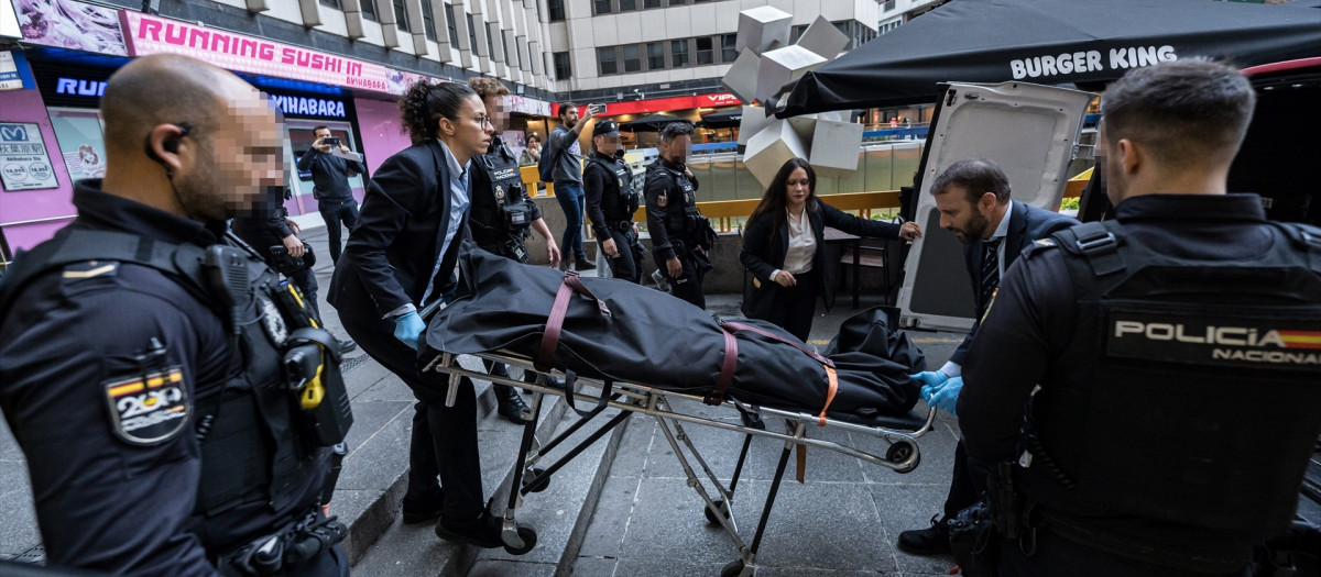 Personal de una funeraria transportan el cuerpo de la fallecida, en la Plaza de los Cubos