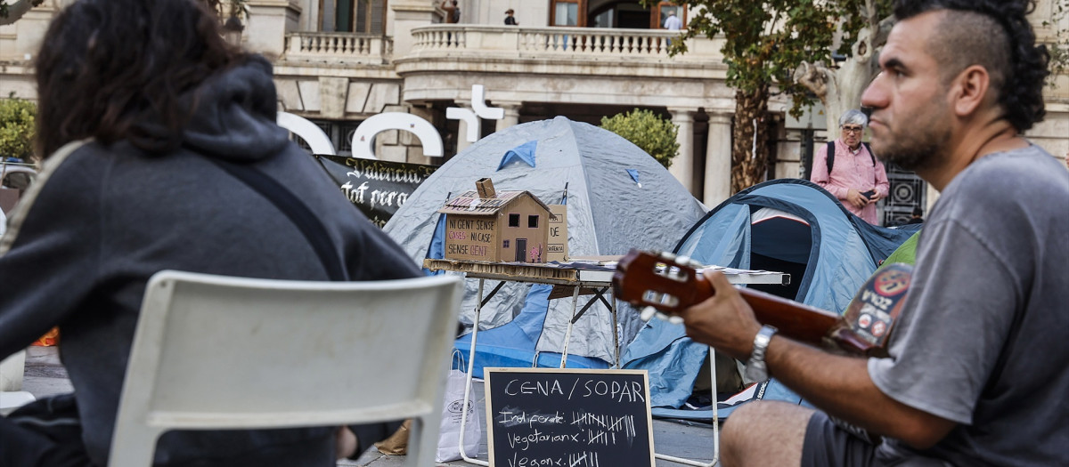 Un hombre toca la guitarra durante la acampada de vivienda en la Plaza del Ayuntamiento de Valencia