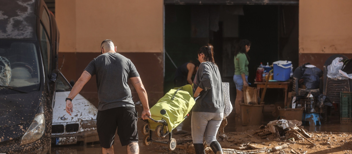 Varias personas limpian los destrozos tras el paso de la DANA en el barrio de la Torre