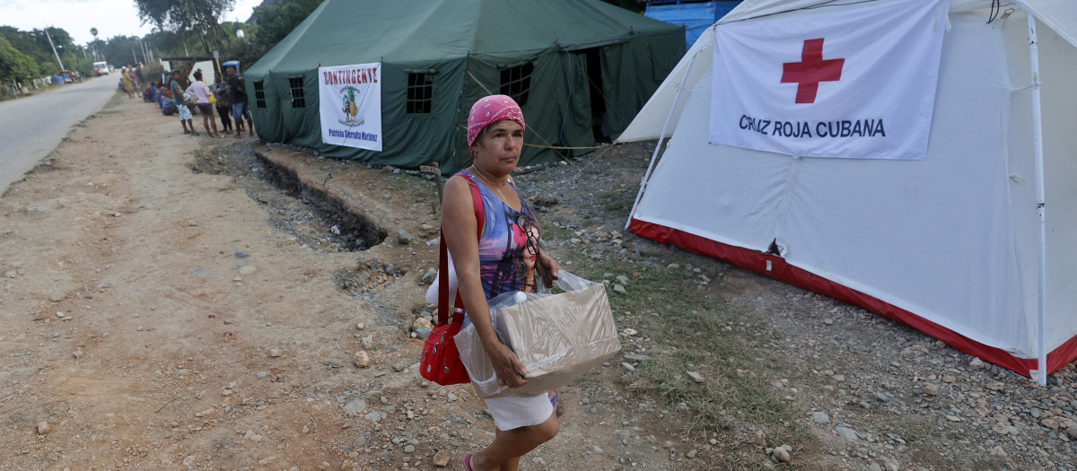 Una mujer carga con una caja de donaciones a la Cruz Roja