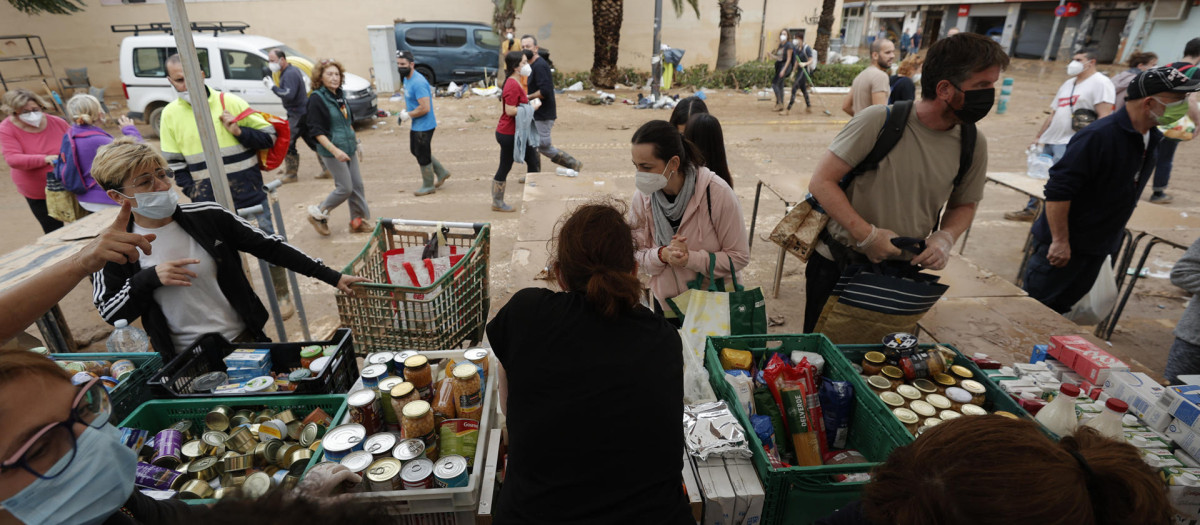 Varios vecinos de Paiporta se acercan a un punto de reparto de alimentos básicos