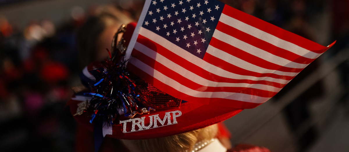 Un partidario lleva un sombrero con una bandera estadounidense y un pin con la palabra "Trump"