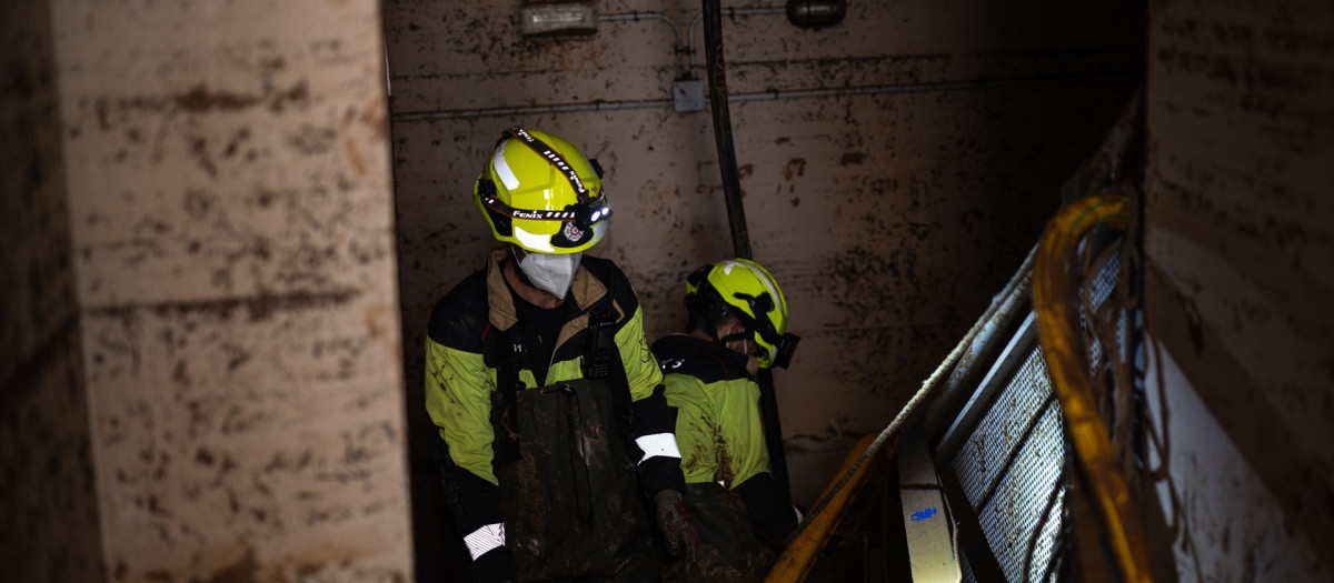 Varios bomberos revisan en Benetúser (Valencia) un garaje inundado por la DANA