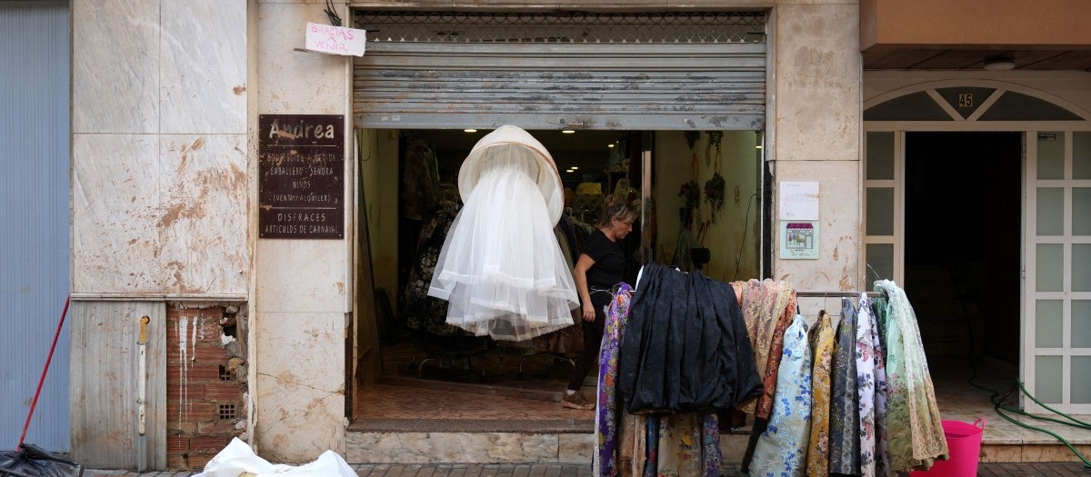 La dueña de una tienda de ropa cuelga su mercancía en la calle de Aldaia, al oeste de Valencia, tras las devastadoras inundaciones