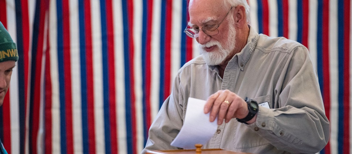 Un hombre deposita una papeleta en las urnas en New Hampshire, el día de las elecciones