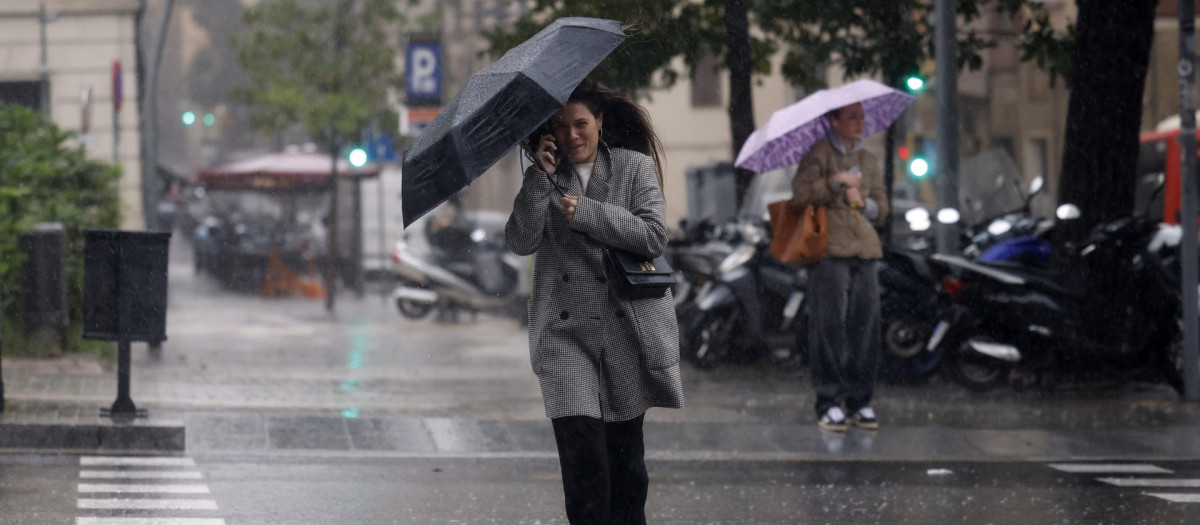 Una mujer se protege de la lluvia en el centro de Barcelona