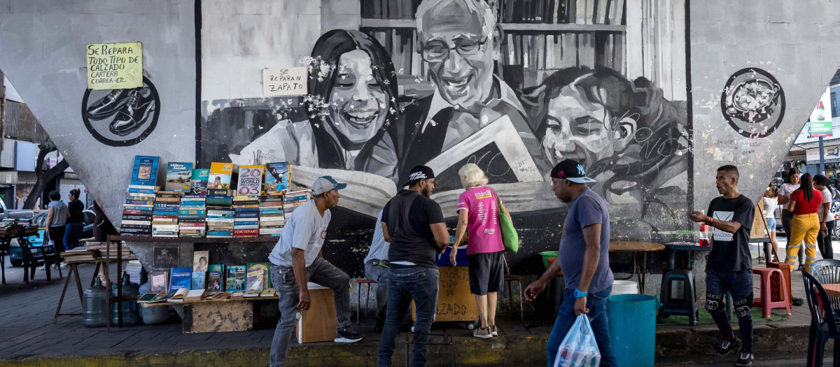 Un grupo de personas caminando frente a vendedores informales de libros en Caracas (Venezuela)