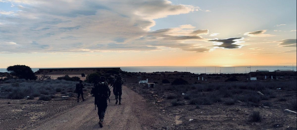 Marcha de endurecimiento de mandos legionarios en Melilla; al fondo, la valla con Marruecos