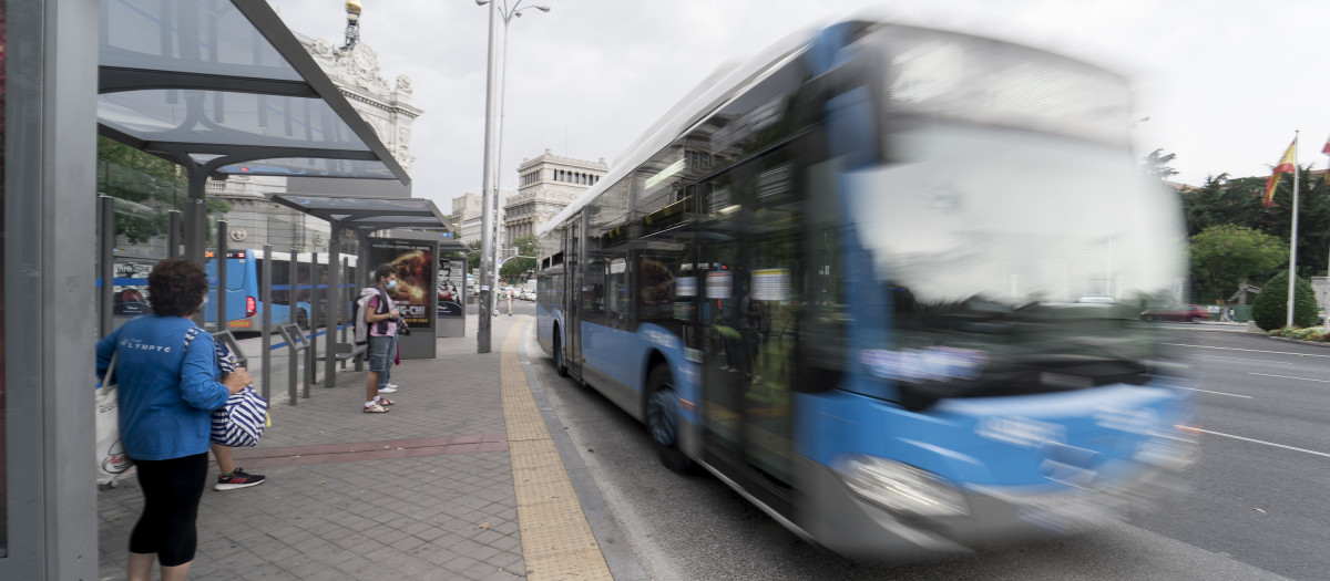 Un autobús de la Empresa Municipal de Transportes (EMT), pasa por una marquesina de la plaza de Cibeles