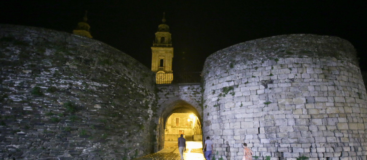 Lugo. Debido a las carencias energéticas, el Gobierno ha puesto en marcha una serie de iniciativas con el fin de incentivar el ahorro energético. En Lugo, monumentos como la Muralla Romana o la Catedral han apagado sus luces y muchos establecimientos han secundado la iniciativa apagando sus escaparates. En la imagen, varias personas entran en la Muralla Romana con la Catedral de fondo, en la noche del miercoles 10 de agosto