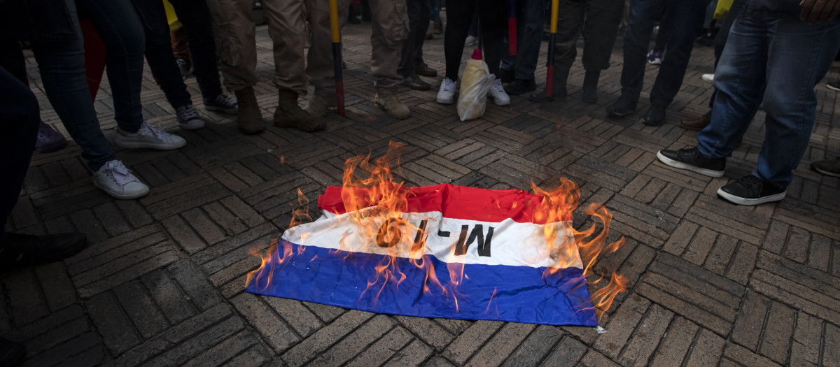 Manifestantes queman una bandera de la guerrilla M-19 durante una protesta contra el gobierno del presidente colombiano Gustavo Petro