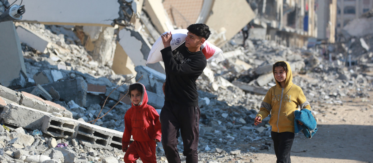 Un niño palestino lleva una bolsa de harina que recibió de un centro de distribución de ayuda en la ciudad de Khan Yunis, en el sur de la franja de Gaza