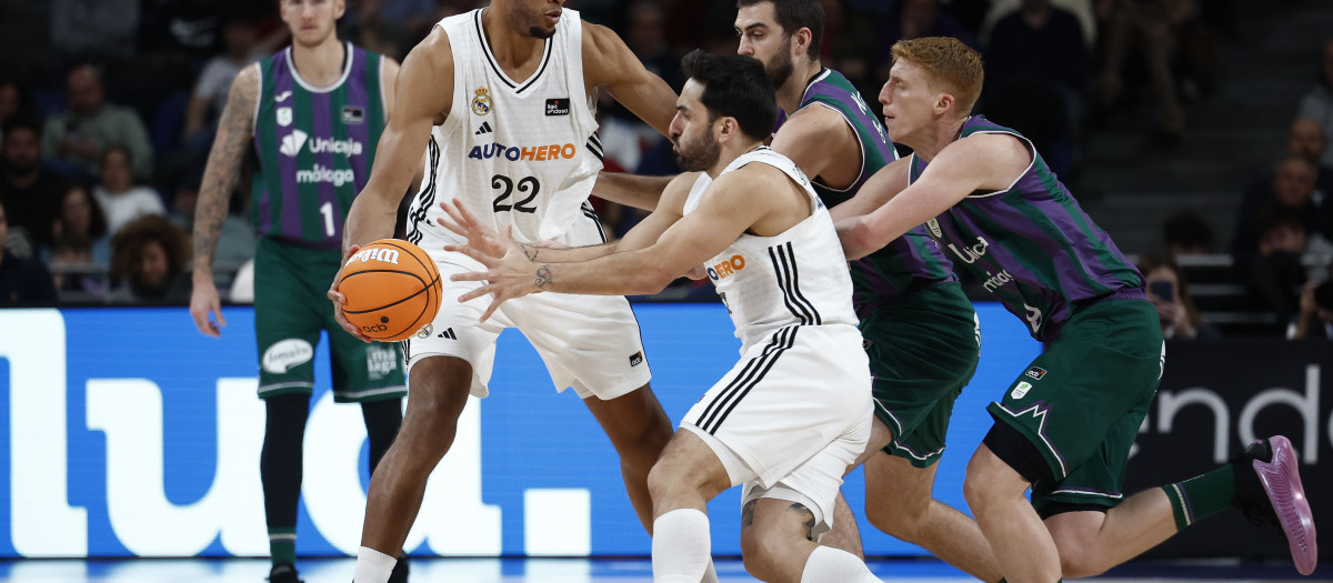 El pívot de Cabo Verde del Real Madrid Edy Tavares (2i) da un pase a su compañero, el base argentino Facundo Campazzo (c) este domingo, durante un partido de baloncesto de la Liga Endesa, entre el Real Madrid y el Unicaja, en Madrid. EFE/ Daniel González