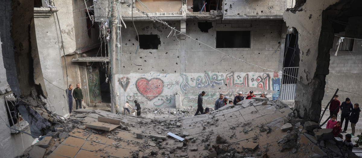 Palestinos junto a un edificio destruido durante un ataque israelí en el campamento de Nuseirat, en el centro de la franja de Gaza