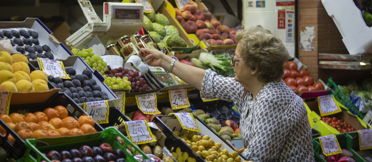 Una mujer compra en uno de los puestos del mercado de abastos de Triana (archivo)