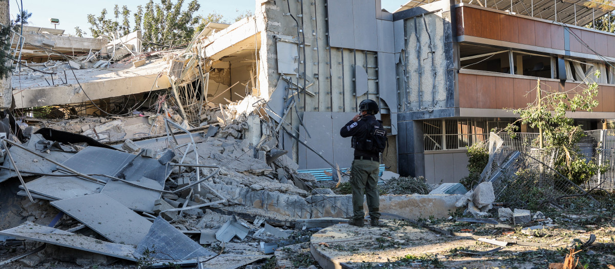 Un miembro de una unidad de desactivación de bombas inspecciona los escombros de un edificio escolar destruido en Ramat Gan, cerca de Tel Aviv