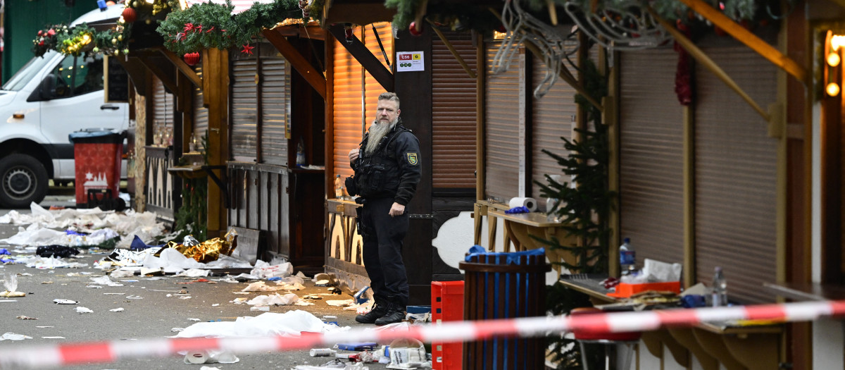 Los escombros de un puesto cerrado se ven mientras un agente de policía se encuentra en el lugar de un ataque con un coche en un mercado navideño en Magdeburgo, este de Alemania