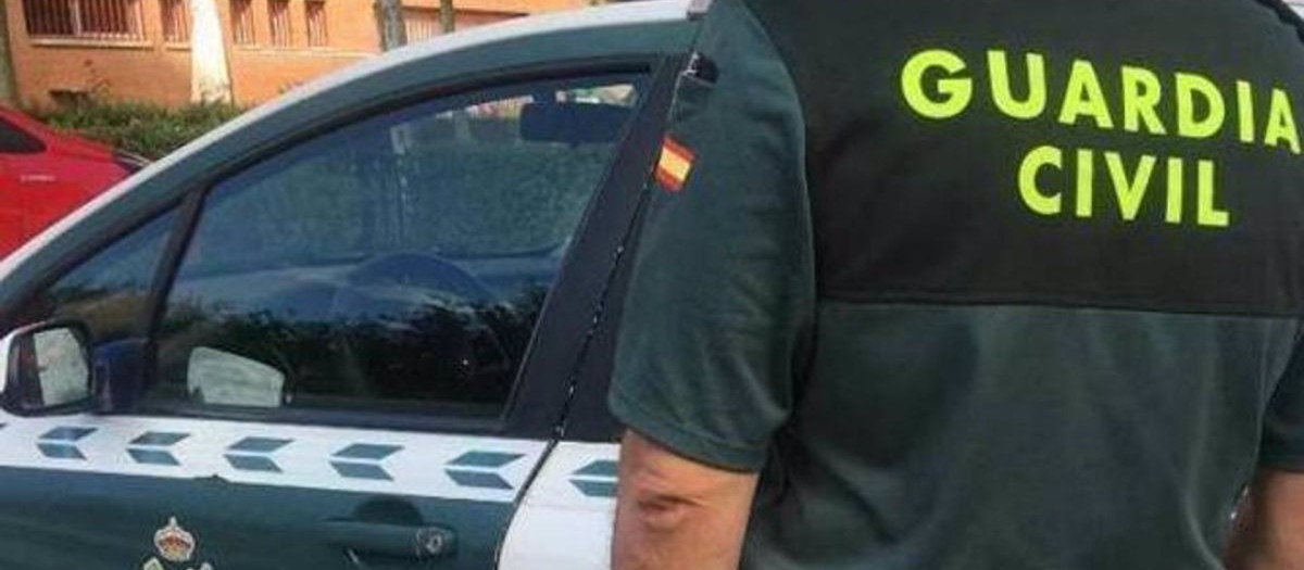 Imagen de archivo de un agente de la Guardia Civil ante un coche patrulla