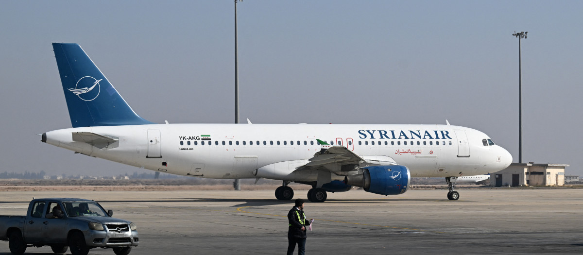 Un trabajador del aeropuerto camina por la pista junto a un avión de Syrian Air en el Aeropuerto Internacional de Damasco