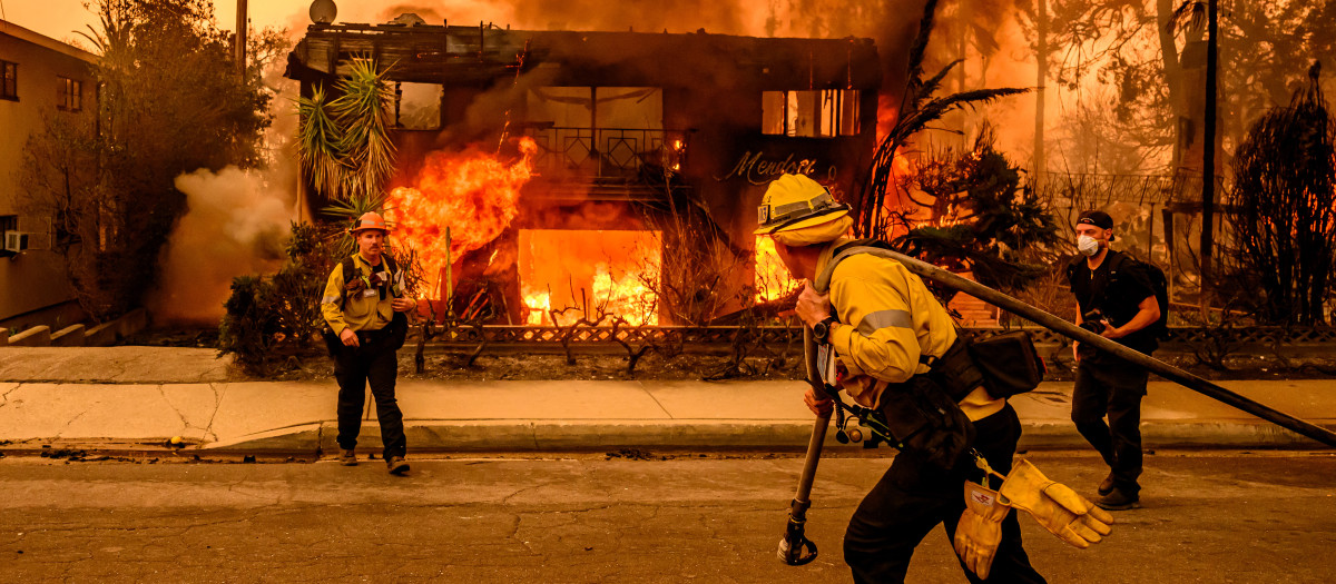 Los bomberos trabajan en el lugar mientras un edificio de apartamentos arde durante el incendio de Eaton en el área de Altadena del condado de Los Ángeles