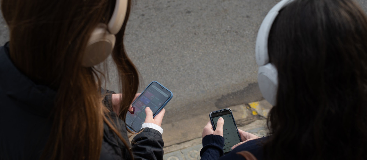 Dos jóvenes usan el teléfono móvil