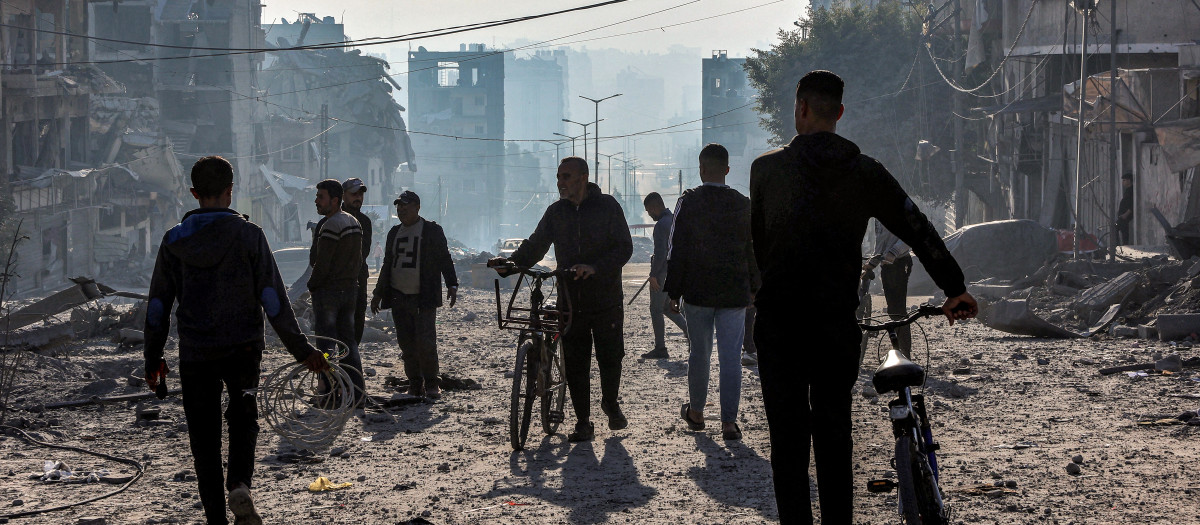 Hombres caminan con bicicletas entre los escombros cerca del lugar del bombardeo israelí en un bloque residencial de la calle Jalaa en la ciudad de Gaza el 14 de enero de 2025