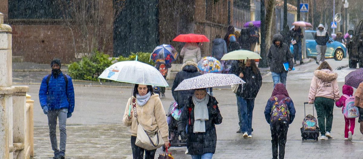 Varias personas caminan bajo la lluvia este lunes en Teruel cuando la Agencia Estatal de Meteorología (Aemet)