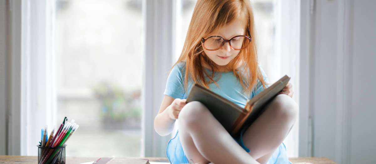 Una niña lee con gafas