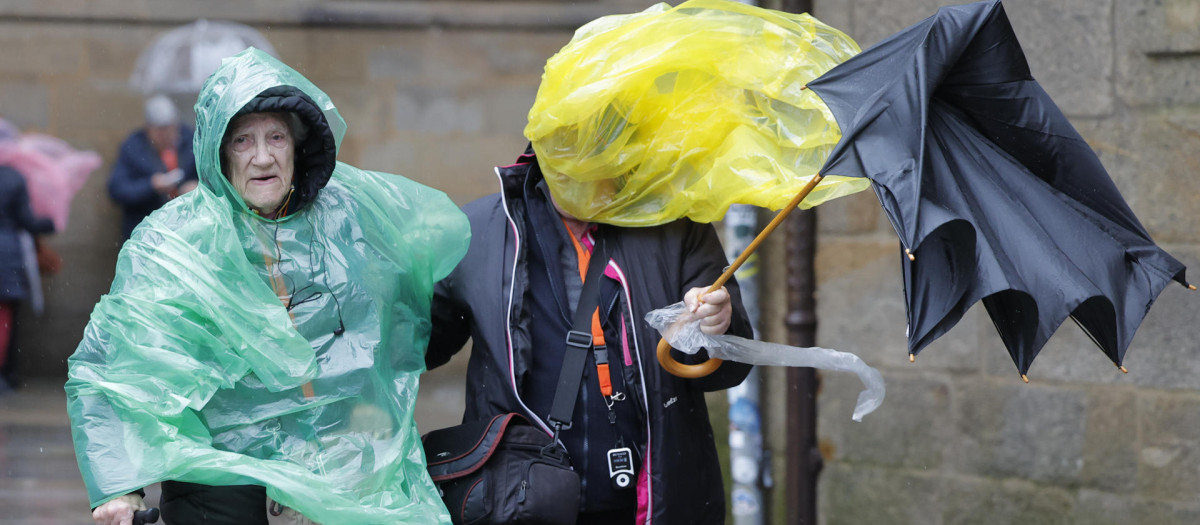 Turistas en la plaza del Obradoiro en Santiago de Compostela con el temporal