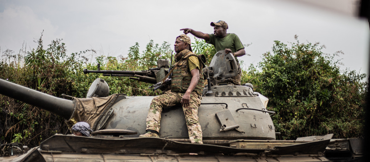 Soldiers of the Armed forces of the Democratic republic of Congo (FARDC) gesture as they ride on top of a tank as they advance towards Sake, 25km north west of Goma on January 23, 2025. A barren plain surrounded by volcanic peaks and where shelters are rare: in this lunar landscape, the Congolese army is fighting to halt the advance of the M23 towards Goma, a city in the east of the Democratic Republic of Congo. (Photo by Jospin Mwisha / AFP)