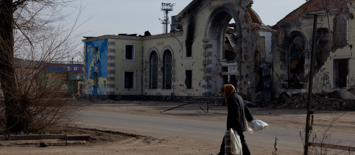 Una mujer con bolsas camina cerca de un edificio dañado en Kostyantynivka, región de Donetsk