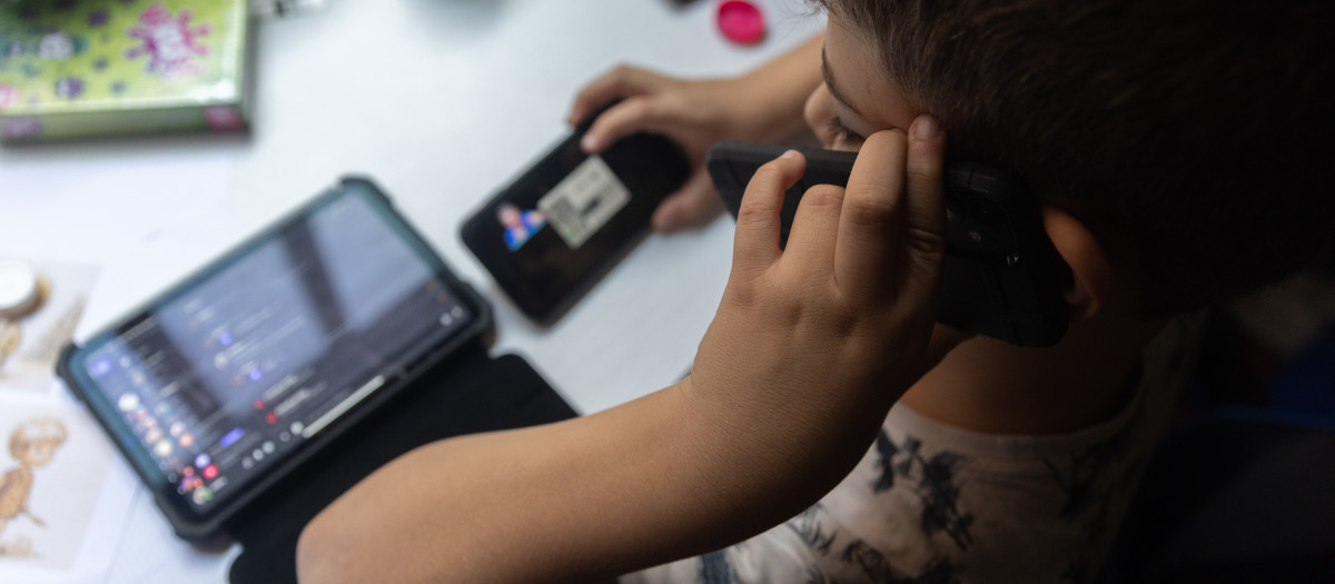 Un niño usa el teléfono móvil y una tablet