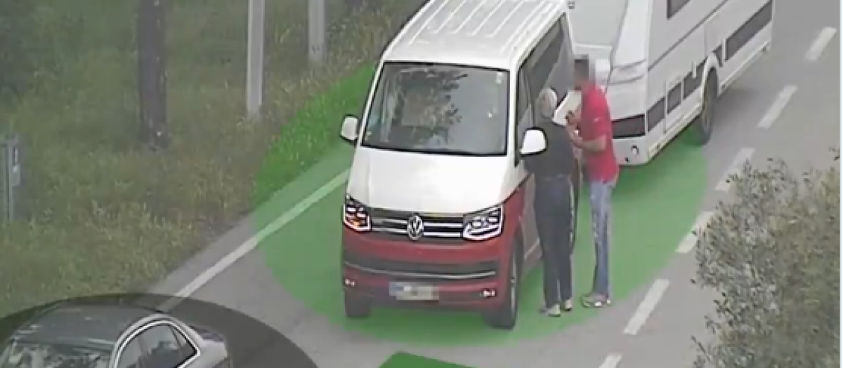 El primer ladrón, de rojo, convence a los dos ocupantes para que se bajen