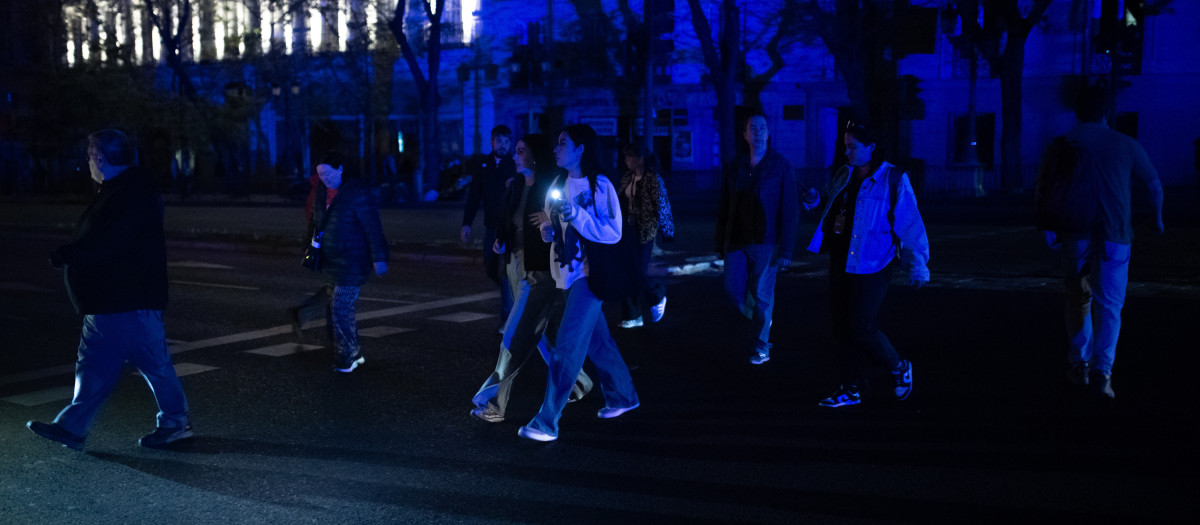 Varias personas cruzan por un paso de peatones tras el apagón eléctrico en Madrid