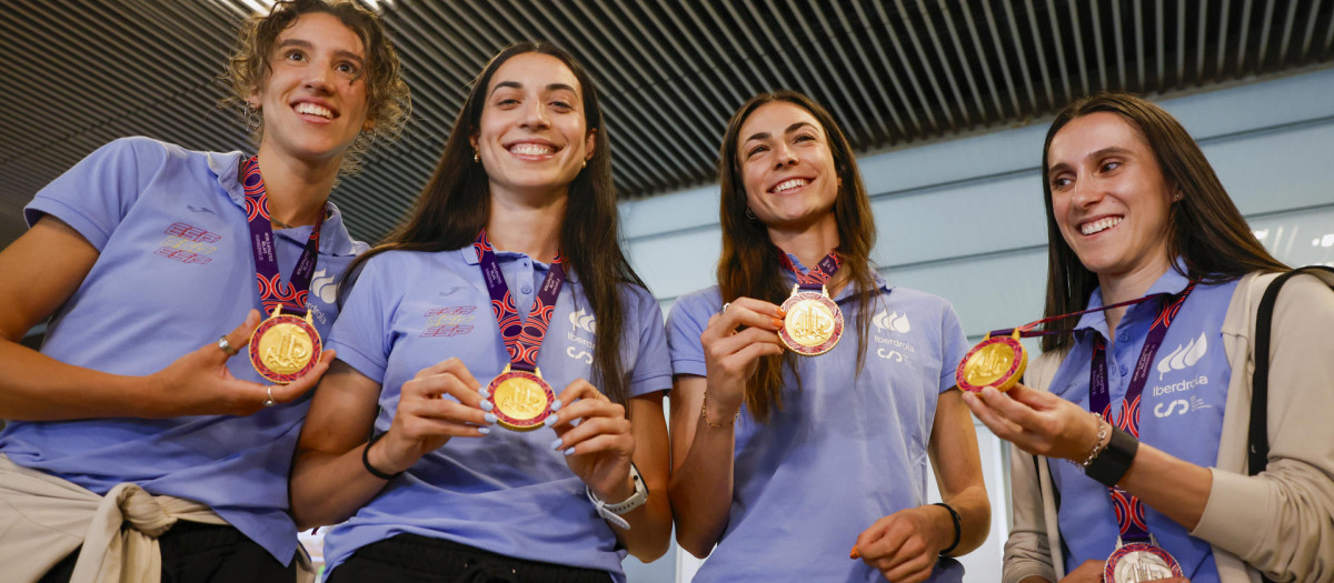 Las componentes del equipo español de relevos femenino 4x400m Daniela Fra (i), Eva Santidrián (2i), Blanca Hervás (2d) y Paula Sevilla muestran la medalla de oro ganada en el Mundial de relevos de Guanzhou (China) a su llegada, este martes, al Aeropuerto Internacional Adolfo Suárez Madrid-Barajas